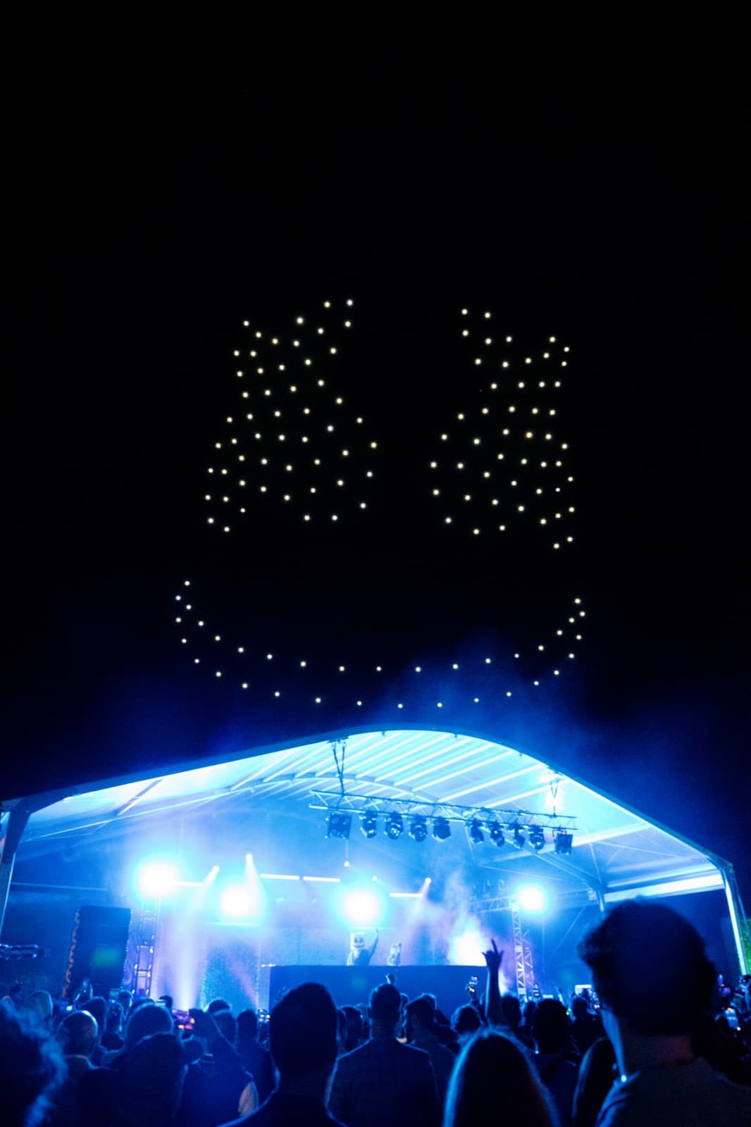 Stage lighting and haze beneath a drone formation